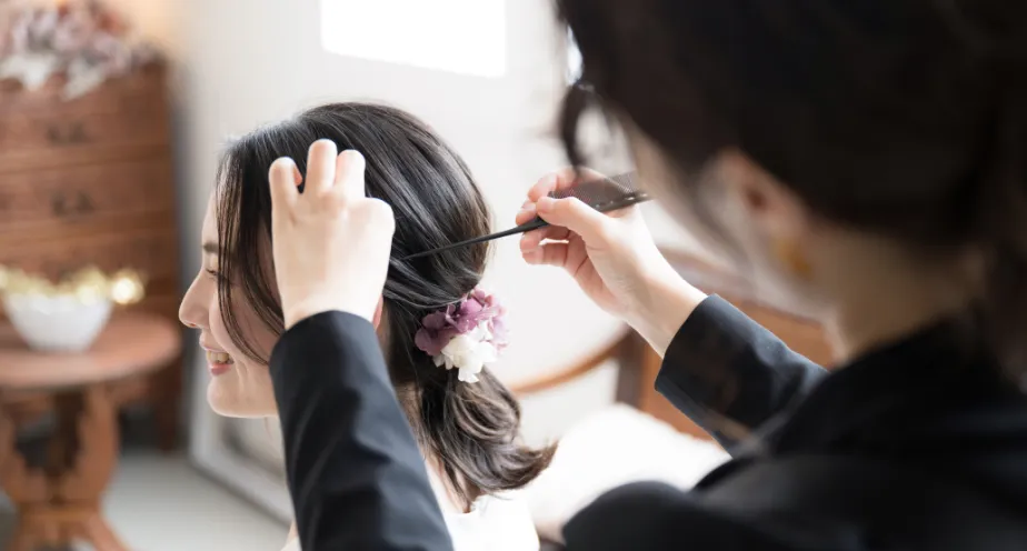花飾りを付けながらヘアセットする美容スタッフの仕事風景